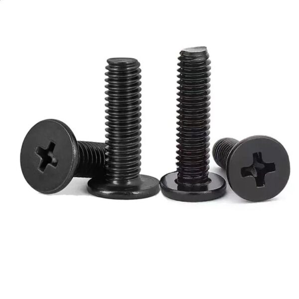 Four Black Oxide Stainless Steel A2 Wafer Flush Phillips Ultra Thin Flat Head Machine Screws, slightly worn at the top, stand upright.