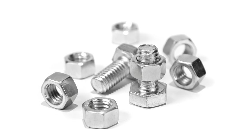 Steel nuts and bolts, essential for maintenance, are scattered on a white surface.