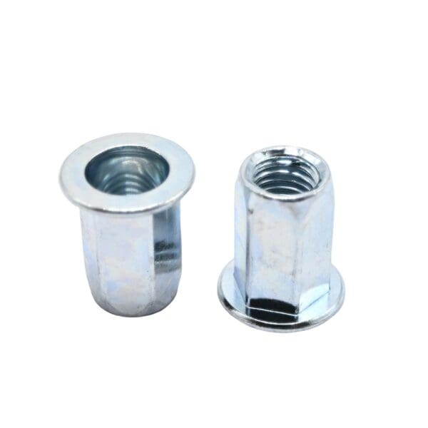 Beyaz zemin üzerinde, biri dik, biri yanda olmak üzere iki adet düz başlı altıgen perçin somunu, dişleri ve flanşlı uçları gösteriyor.