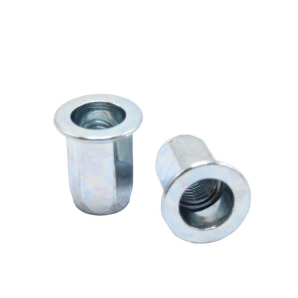 Beyaz zemin üzerinde iki adet düz başlı altıgen perçin somunu; biri dik, biri yan yatmış.