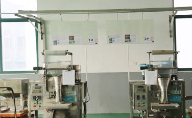 Duvarda grafikler ve diyagramlar bulunan temiz ve aydınlık bir odada yan yana duran iki endüstriyel paketleme makinesi.