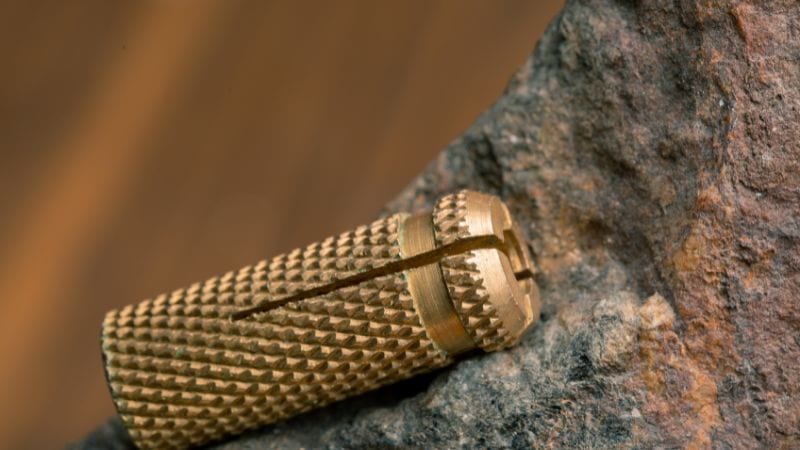 Beton kullanımı için kısmen kaba taşa yerleştirilmiş pirinçten yapılmış bir duvar dübeli dübelinin yakın çekimi.