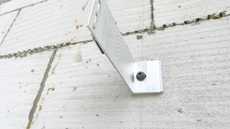 Beyaz beton duvara bir vida ve pul ile monte edilen metal L braketi, Drop-In Ankraj kullanımına uygundur.