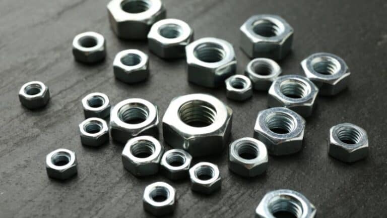 Hex nuts of various sizes are scattered on a dark, textured surface.