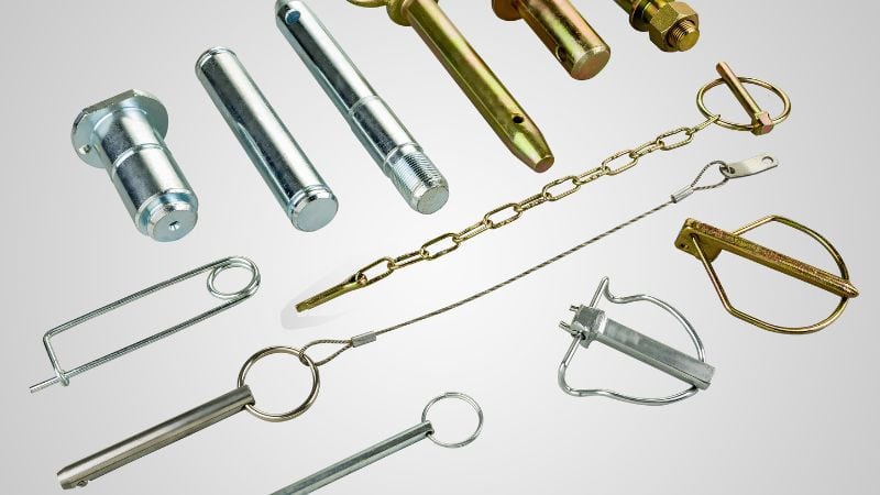 Assorted metal pins, chains, and locking fasteners in various shapes and sizes are arranged on a light background.
