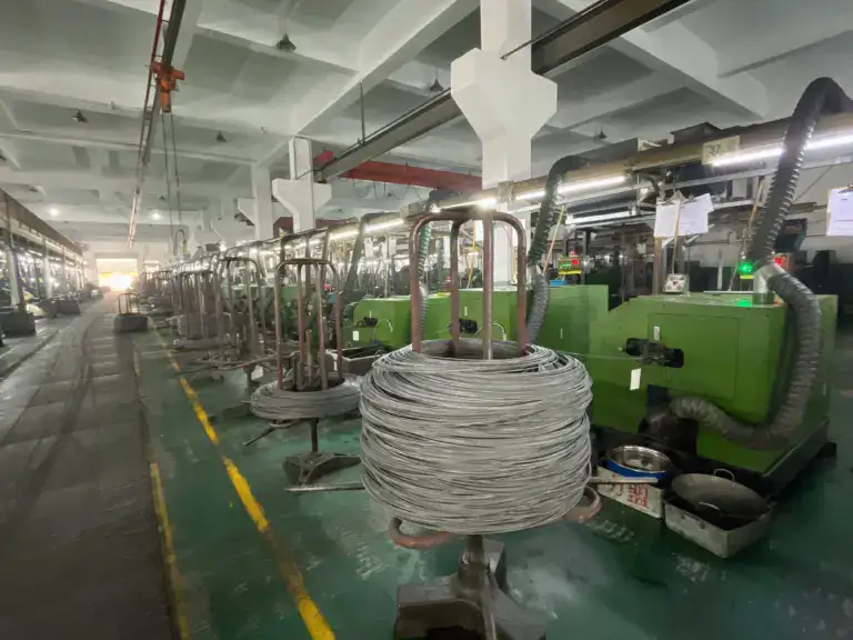 Industrial wire manufacturing machinery in a factory setting, featuring coiled wire spools and advanced production equipment for high-volume wire processing.